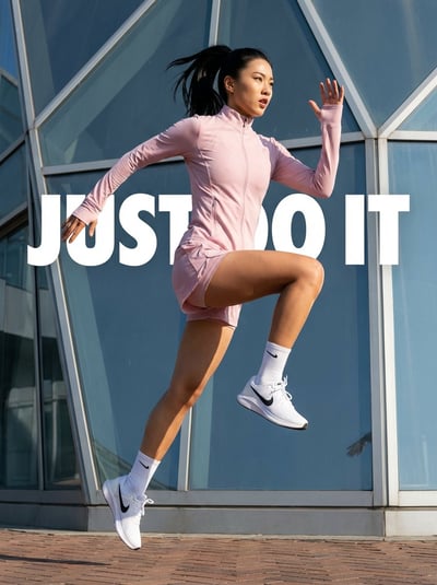 Mid-Air Asian Runner in Pastel Pink with “JUST DO IT” Typography on Geometric Glass Facade thumbnail