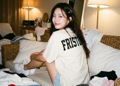 Vintage Film-Style Lifestyle Photo of a Girl Looking Over Her Shoulder on a Woven Sofa thumbnail